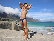 Cute slim gay guy stripping out of his speedo swimwear.
